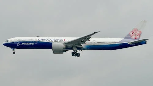 Free Side view of a China Airlines Boeing 777 airplane flying against a cloudy sky. Stock Photo