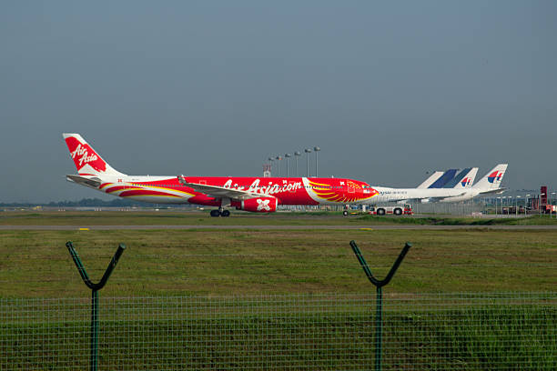 AirAsia X Airbus A330-343 aircraft Kuala Lumpur, Malaysia, April 14, 2017 - AirAsia X Airbus A330-343 aircraft with registration number 9M-XXT on the Airport Tarmac, The aircraft is being towed to a technical hangar at Kuala Lumpur International Airport, Malaysia. In the background there are several Malaysian airlines cargo planes of the Boeing 747 fleets. airasia-airbus-a320 stock pictures, royalty-free photos & images