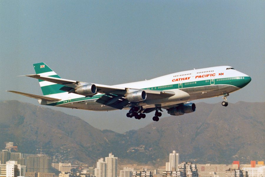 View of an older livery on a Cathay Pacific aircraft flying through the sky.