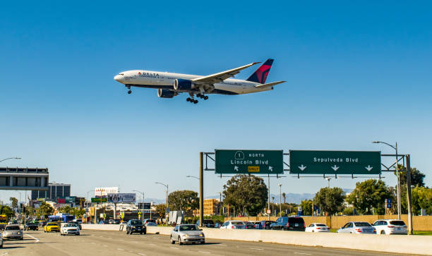 Delta Air Lines Jet Flying Over LA Freeway A Delta Air Lines Boeing 777 flies over the Pacific Coast Highway moments before touchdown onto Runway 27R at Los Angeles International Airport (LAX) on May 21, 2017 delta 777 stock pictures, royalty-free photos & images
