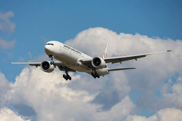 Japan Airlines Boeing 777 aircraft as seen flying on final approach during a blue sky summer sunny day with some clouds, arriving from Tokyo...
