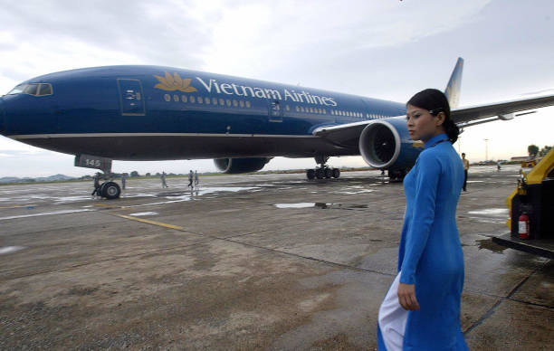 Vietnam Airlines ground hostess wearing a traditional dress walks toward a new Boeing 777-200ER which landed at Hanoi's Noi Bai airport, 19 September...