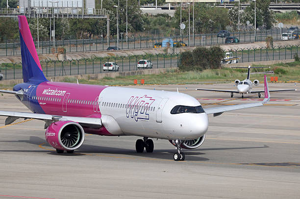 Wizz Air Airbus A321-271NX and a GlobeAir Cessna Citation Mustang are on the runway for takeoff from Barcelona-El Prat Airport, in Barcelona, Spain,...
