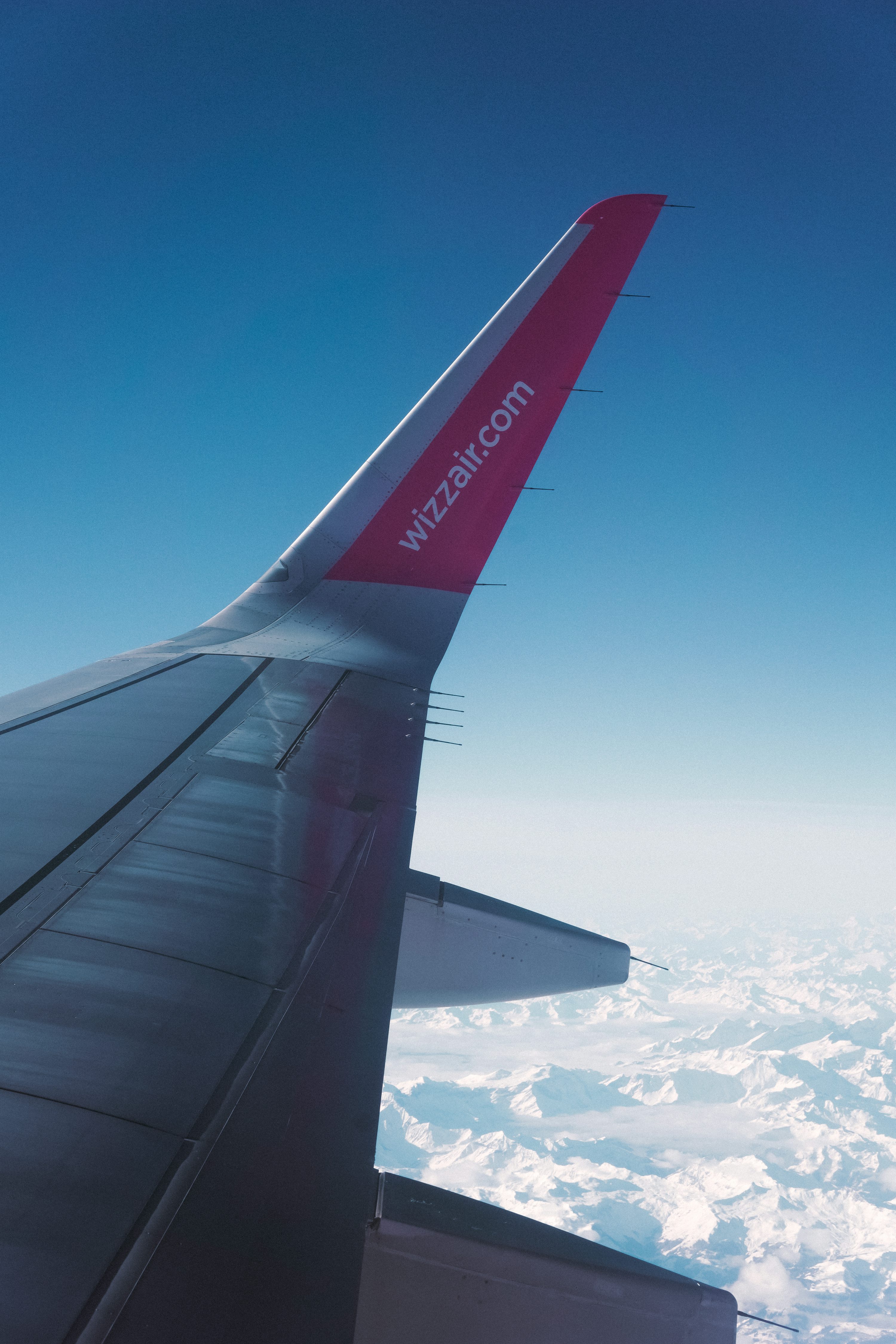 A wizz air wing is flying high in the sky.