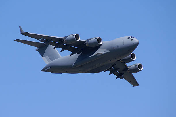 military jet cargo airplane C17 Globemaster flying in blue sky Military cargo jet airplane against clear blue sky. C-17 c 17 globemaster stock pictures, royalty-free photos & images