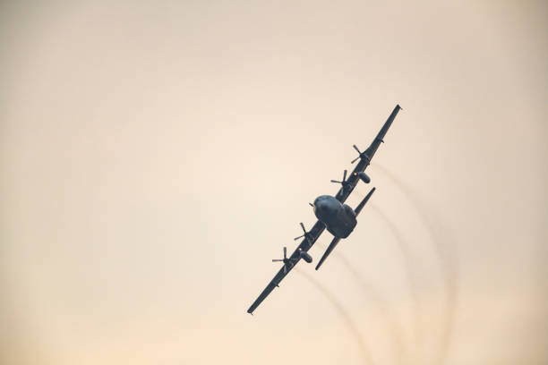 lockheed c-130 hercules military airplane flying in mid air during sunset - military plane cargo stock pictures, royalty-free photos & images
