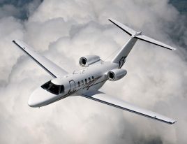Cessna Citation CJ4 flying above clouds with clean white livery and swept wings