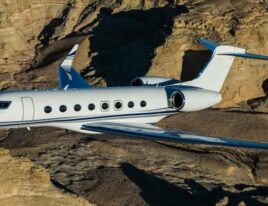 Gulfstream G650ER private jet flying over rugged desert canyon terrain