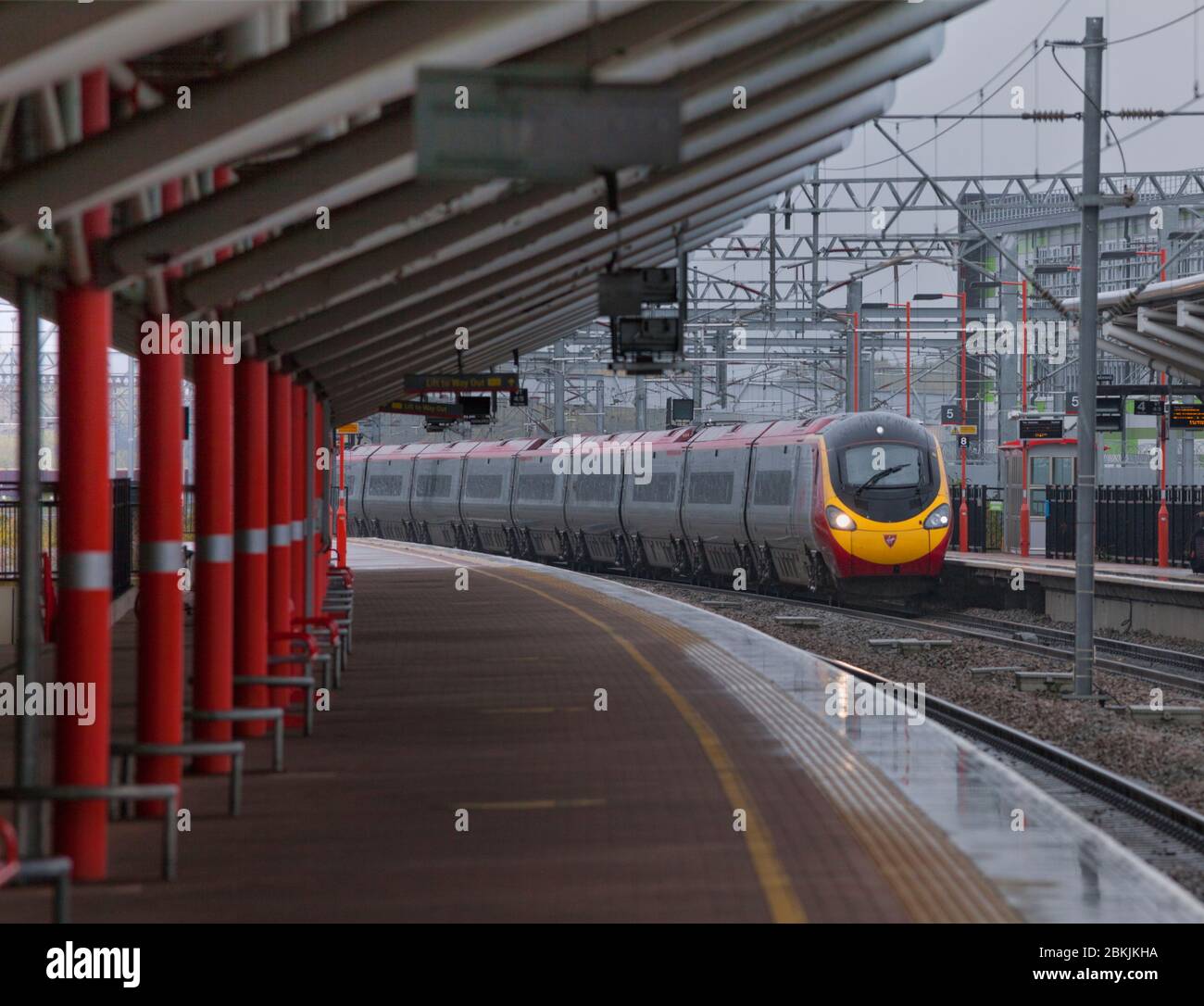 Virgin Trains Alstom class 390 Pendolino train passing Rugby railway station in the rain with the station canopy. - Stock Image