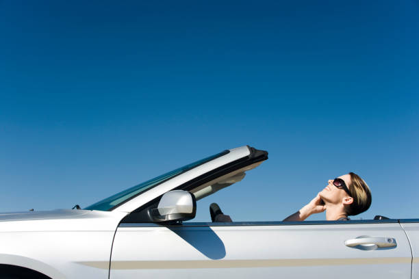 woman talking on cell phone while driving convertible - convertible car side view stock pictures, royalty-free photos & images