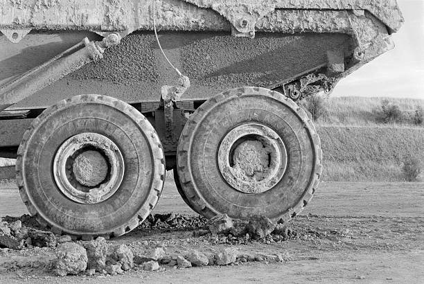 dump truck on construction site, side view (b&w) - dump truck side view stock pictures, royalty-free photos & images