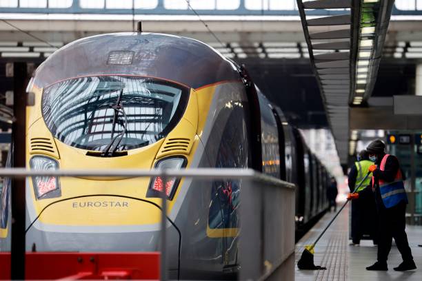 Workers clean the platform area as a Eurostar train bound for Paris prepares to leave St Pancras International train station in London on January 18,...