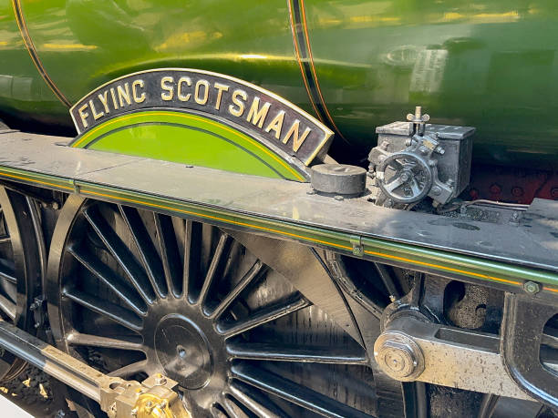 Side view of the famous Flying Scotsman historic steam locomotive Cardiff, Wales - 8 June 2023: Close up view of the side of the famous Flying Scotsman steam engine at Cardiff Central railway station, showing the brass name plate and one of the main wheels. the flying scotsman train stock pictures, royalty-free photos & images