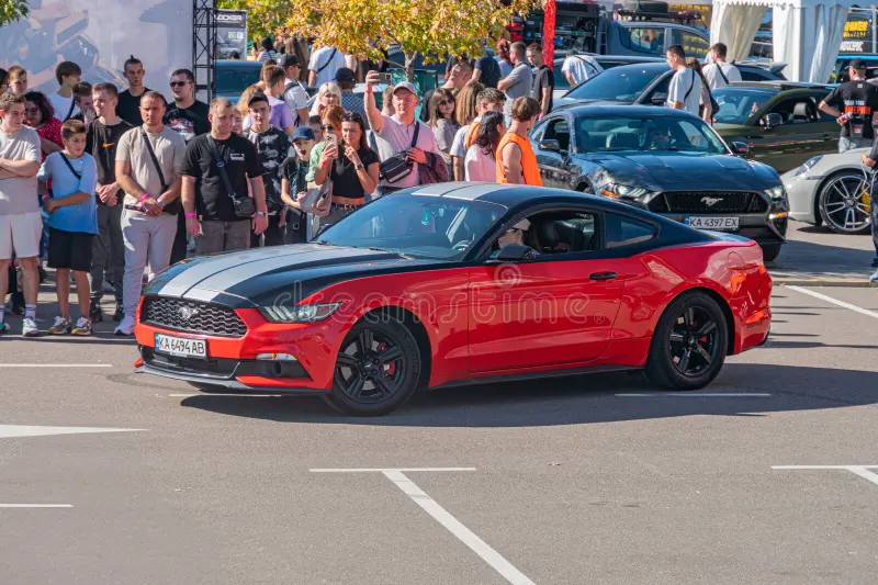Red Ford Mustang at a car show, crowd admiring, outdoor setting, glossy finish, daytime lighting, casual to semi-formal attire, other cars, backpacks, handbags, Kyiv, Ukraine - September 21, 2025. Mustang side view stock images, royalty-free photos and pictures