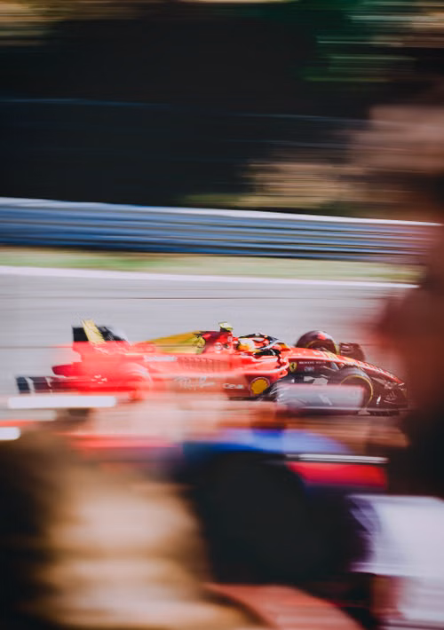 Free A fast-moving red Formula One car speeding on a racing track, showcasing blurred motion and excitement. Stock Photo