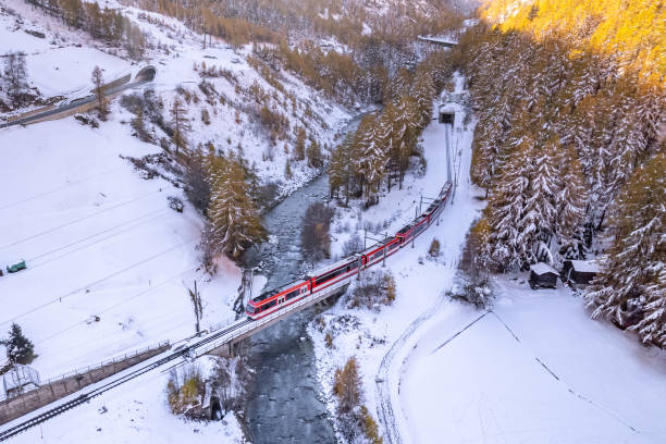 Swiss Ski Train Passing Over A Bridge A red train in Switzerland used to transport passengers and designed to climb steep mountains to take skiers to the resorts in the alps. glacier-express-switzerland stock pictures, royalty-free photos & images