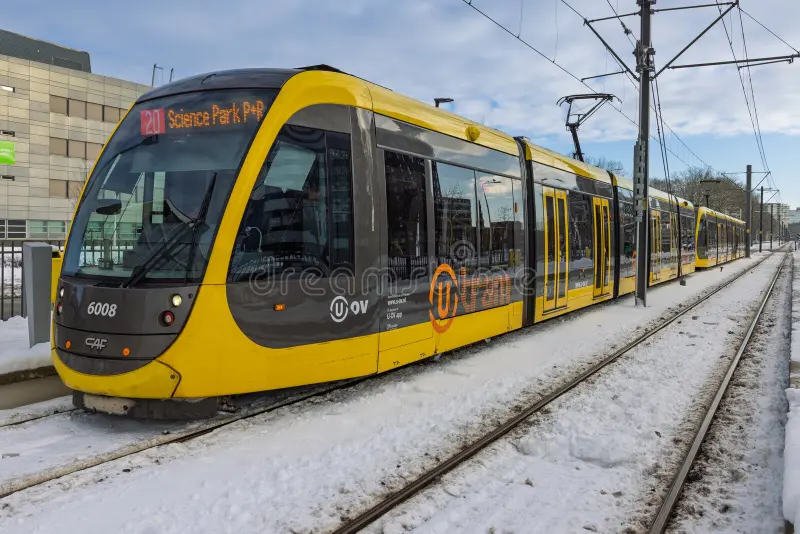 Side view of a modern yellow and grey electric tram waiting at a station in Utrecht with snow covering the tracks, platform, and surroundings. Utrecht Netherlands, 6 january 2026. Ice train side view stock images, royalty-free photos and pictures