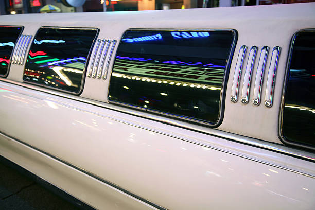 Detail Of Limousine With Neon Reflections Side view of limo parked on curb at night in Times Sqaure, New York City, NY, USA. long limousine stock pictures, royalty-free photos & images