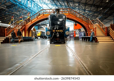 York, England - 7 June 2025: Famous Mallard steam locomotive seen under a steam era footbridge at a railway museum in North Yorks. The aerodynamic design of the world speed record train is evident. Editorial Stock Photo