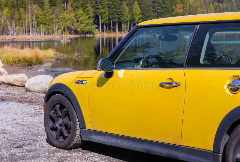 Side view of a Yellow Mini Cooper S car on natural background. Yellow Mini Cooper parked in the park-April 27,2022-Whonnock Lake BC, Canada-Travel photo, nobody, selective focus. Bmw mini cooper car side view stock images, royalty-free photos and pictures