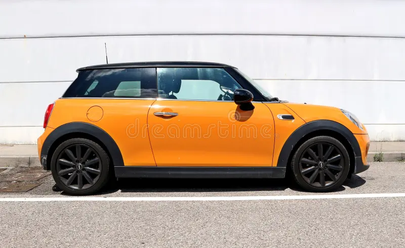 Udine, Italy. August , 6 2021. Side view of an orange Mini Cooper, or Mini Hatch, parked on the roadside. Concrete wall on background. Bmw mini cooper car side view stock images, royalty-free photos and pictures