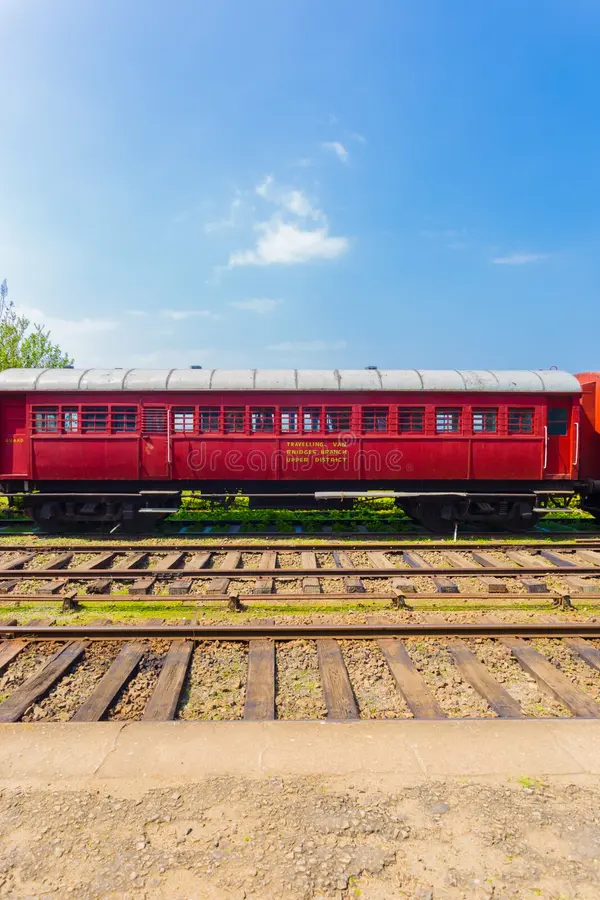 Side view of an old stationary red passenger carriage car sitting parked on train tracks, part of Sri Lanka Railways, on a blue sky day. Vertical. Passenger train side view stock images, royalty-free photos and pictures