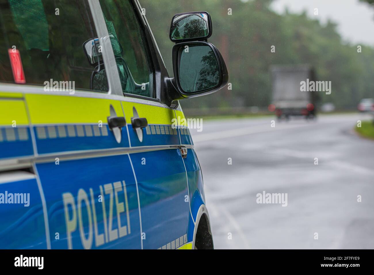 Side view of German police car with motorway in the background. Mirror window body from the passenger side with yellow and blue paintwork. Emergency b - Stock Image