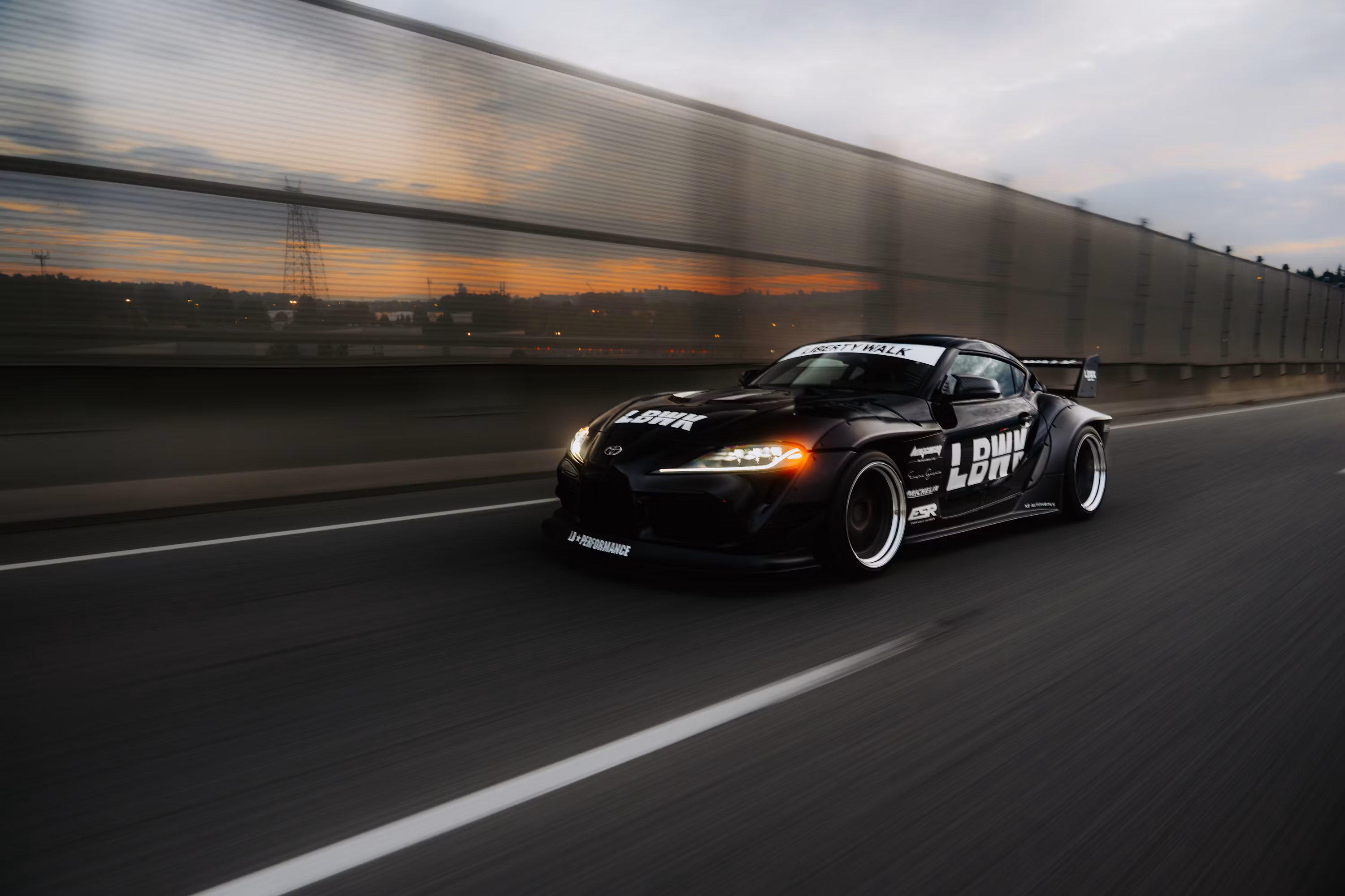 A fast black sports car races down the highway
