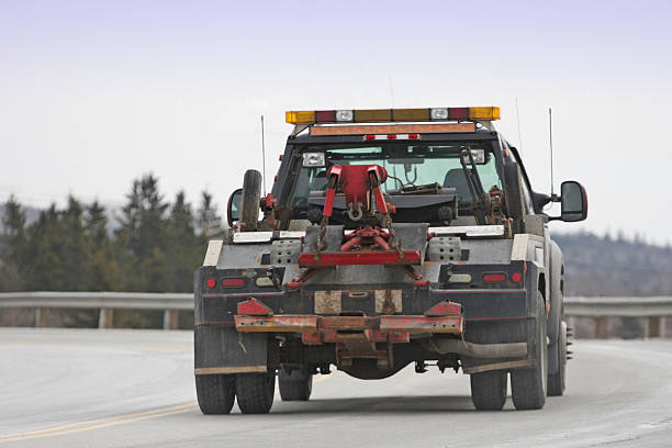 Tow Truck Rear view of a nondescript tow truck travelling on a highway.  Shallow dof with some motion blur. tow truck back view stock pictures, royalty-free photos & images